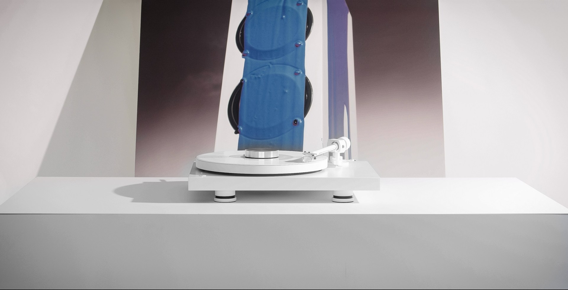 Pro-Ject Debut Pro White Edition in front of a picture with a speaker on it