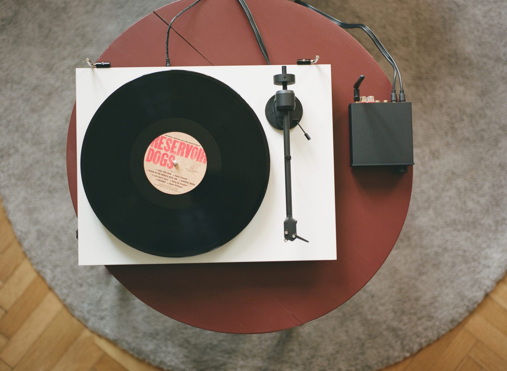 Pro-Ject E1 record player in white on a red coffee table with a record on it