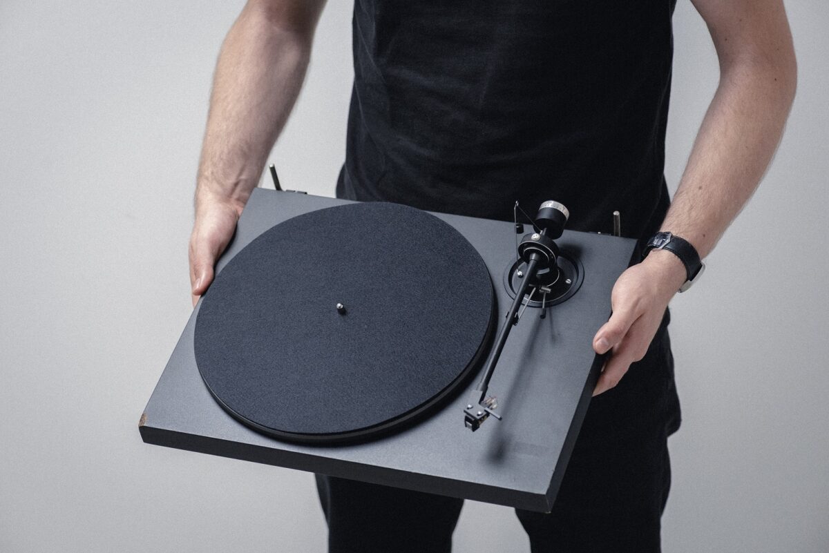 Ein Man haltet einen Pro-Ject Plattenspieler in seinen Händen