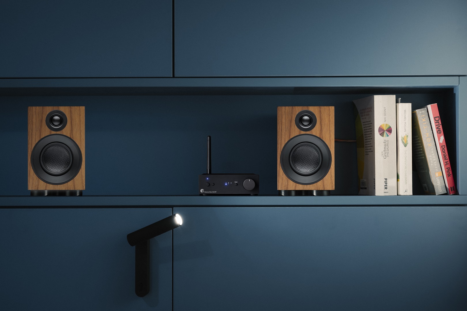 Speaker Box 3e Carbon Walnut+stereo Box S3 Bt in a blue shelf with books playing music